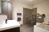 Badezimmer mit bodengleicher Dusche und Badewanne - Moderne 2-Zimmer-Wohnung mit Balkon im 1. Obergeschoss